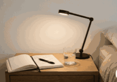 Caderno e luminária em mesa de cabeceira representando rotina noturna